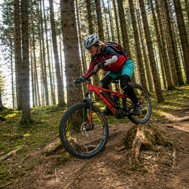 E-Mountainbikerin trainiert Traktion, Balance und den Einsatz der Motorunterstützung am Berg